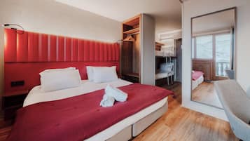 Ein modernes Hotelzimmer mit einem großen Bett, einem Holzschrank, einem Schreibtisch und einem Sessel.