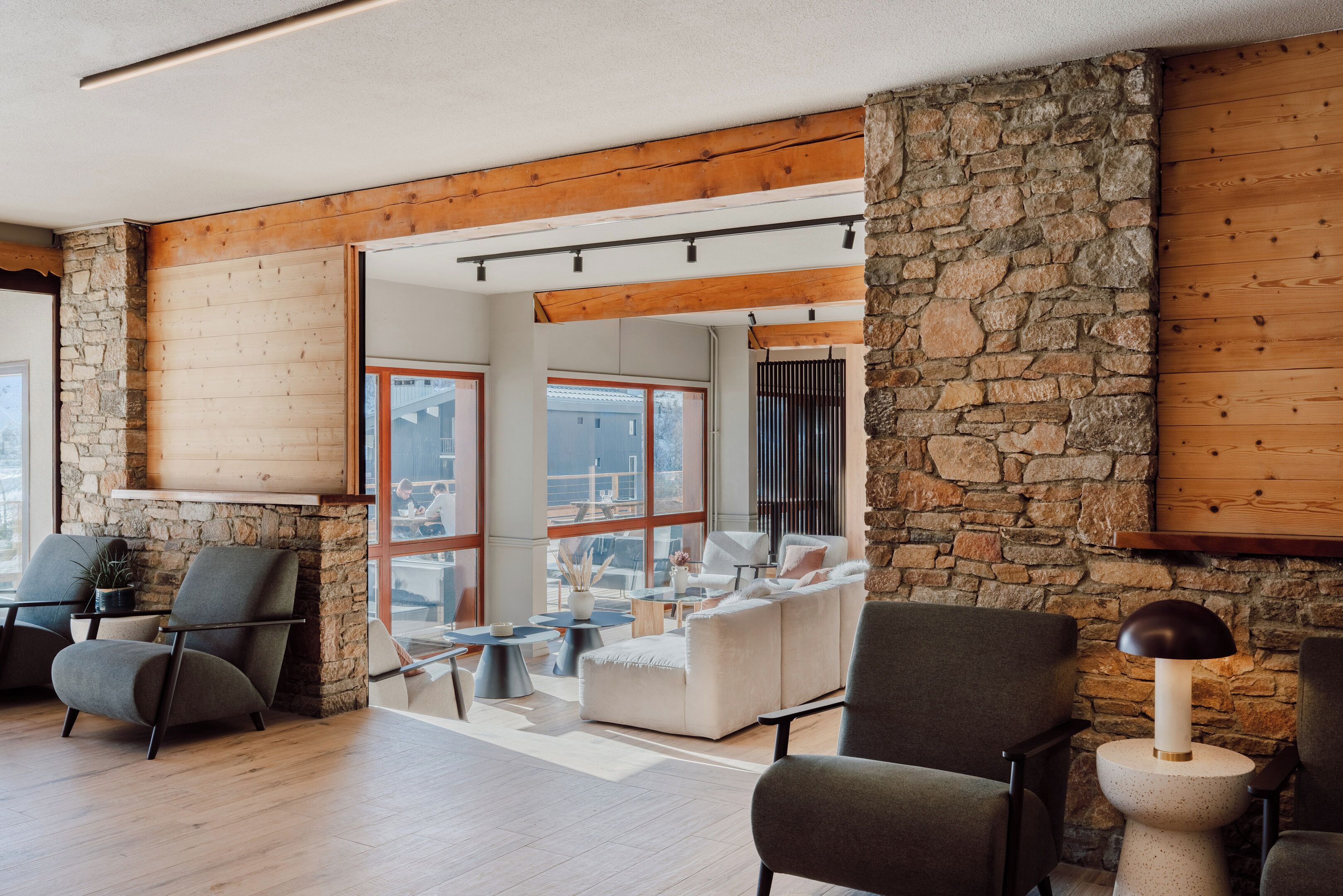 Un salon moderne avec des murs en pierre, des poutres en bois et une grande fenêtre.