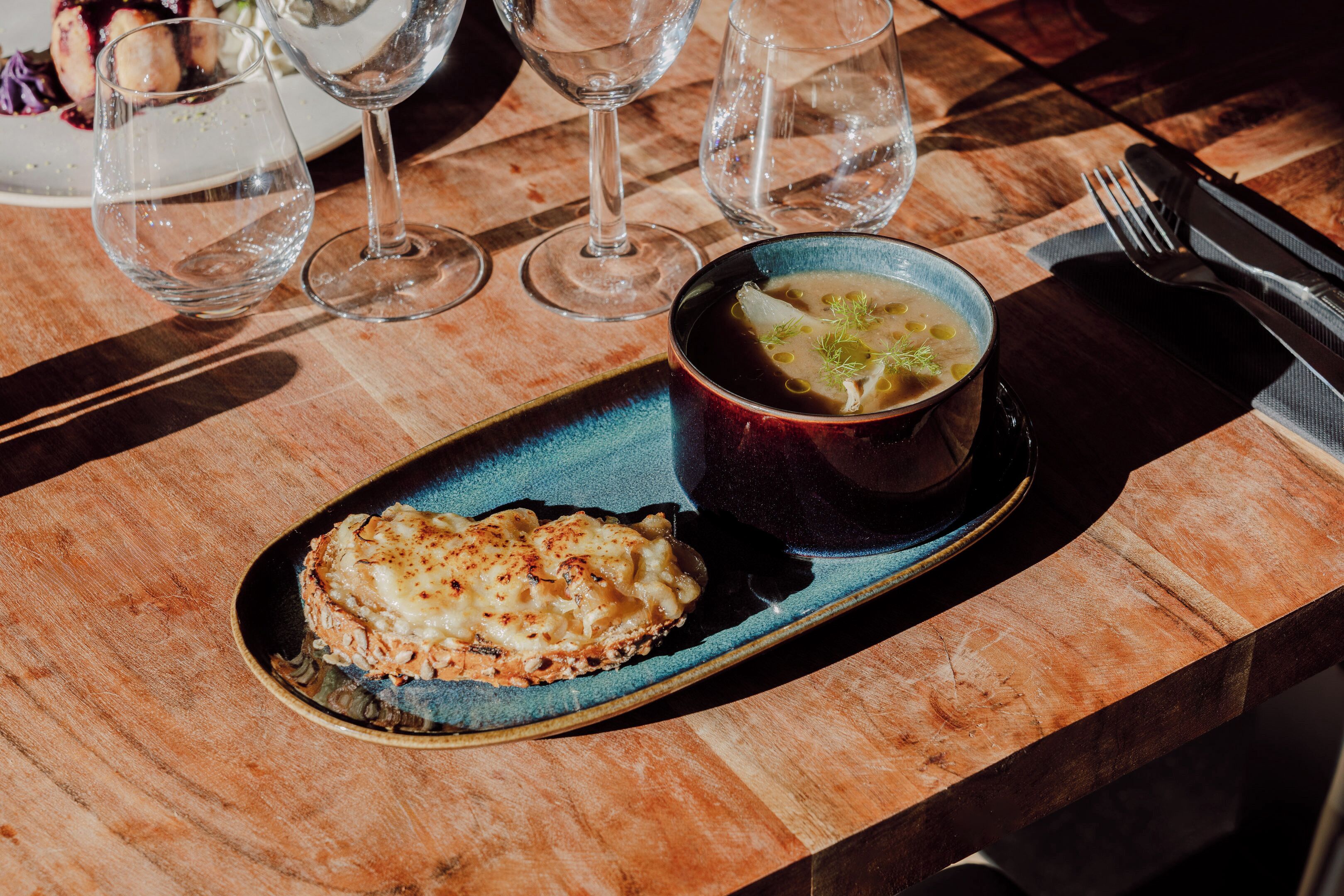 Una mesa de madera con un plato azul que contiene un plato y un cuenco de sopa.
