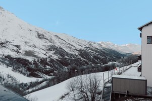 A snow-covered mountain landscape with a building featuring a staircase and a small structure on the right.