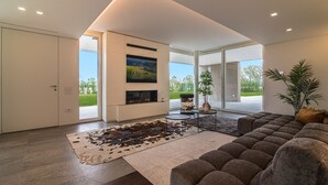 Una sala de estar moderna con un amplio sofá modular, un televisor de pantalla plana montado en la pared y una chimenea.