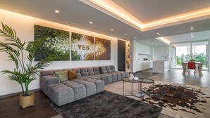 Una sala de estar moderna con un sofá seccional gris, un cuadro abstracto grande y un tapiz de cuero de vaca.