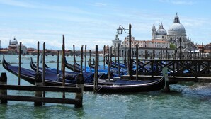 Gondolas amarradas en un muelle, con un edificio histórico al fondo.