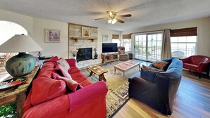 A spacious living room with a red sofa, blue armchair, and a fireplace.