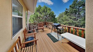 A wooden deck with outdoor furniture, including chairs and a table, and a barbecue grill.