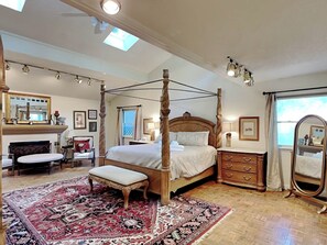 A four-poster bed with a canopy, a sitting bench, a fireplace, and a large mirror. - Blue Duck Lodge | River View, Pet-Friendly (Ruidoso)