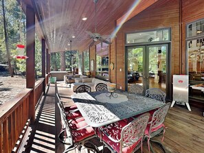 An outdoor patio area with a long table and chairs, wooden deck, and a view of the restaurant inside.
