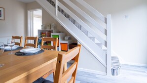 A dining area with a wooden table and chairs, a staircase with white railings, and a bookshelf with various items. - 3 Bedroom family home | Parking | Garden - Pass the Keys (Stroud)