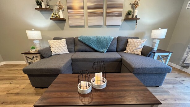 Ein modernes Wohnzimmer mit einer Eckcouch, einem Holztisch und Wanddekoration.