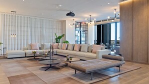 A modern living room with a sectional sofa, two round coffee tables, and a large window providing natural light. - Exclusive 3BD Penthouse on 50th Floor,  Direct Water & City Views (Miami)