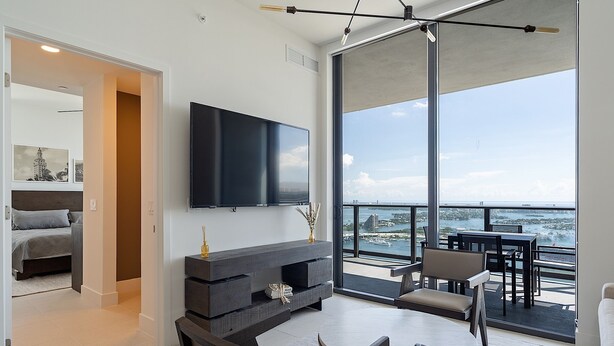 A modern living room with a large TV, a fireplace, and a balcony with a view of the sea. - Exclusive 3BD Penthouse on 50th Floor,  Direct Water & City Views (Miami)