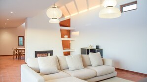 Ein modernes Wohnzimmer mit Ecksofa, eingebauten Regalen, Kamin und Pendelleuchten.