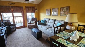 A living room with a sofa, a dining table with a placemat, and a ceiling fan. - Cozy, Clean & Comfortable Condo, less than 2 miles to Silver Dollar City (Reeds Spring)
