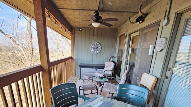 A covered patio with a table and chairs, a ceiling fan, and a clock on the wall. - Cozy, Clean & Comfortable Condo, less than 2 miles to Silver Dollar City (Reeds Spring)
