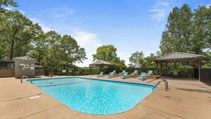 A swimming pool with lounge chairs and gazebos, surrounded by trees. - Cozy, Clean & Comfortable Condo, less than 2 miles to Silver Dollar City (Reeds Spring)