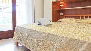 Un dormitorio con cama, mesita de noche, lámpara y ventana con cortinas.