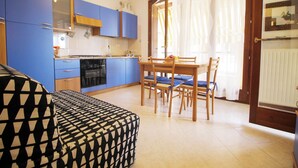 Una cocina compacta con armarios azules, una mesa de comedor con sillas y un sofá estampado.