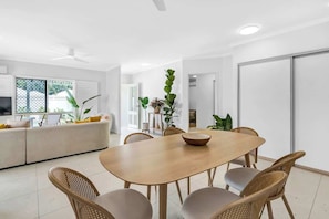 Un salon moderne comprenant une table à manger, des chaises en osier, un canapé et un téléviseur.