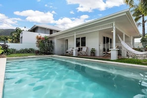 Una casa moderna con piscina, area relax all'aperto e un'amaca.