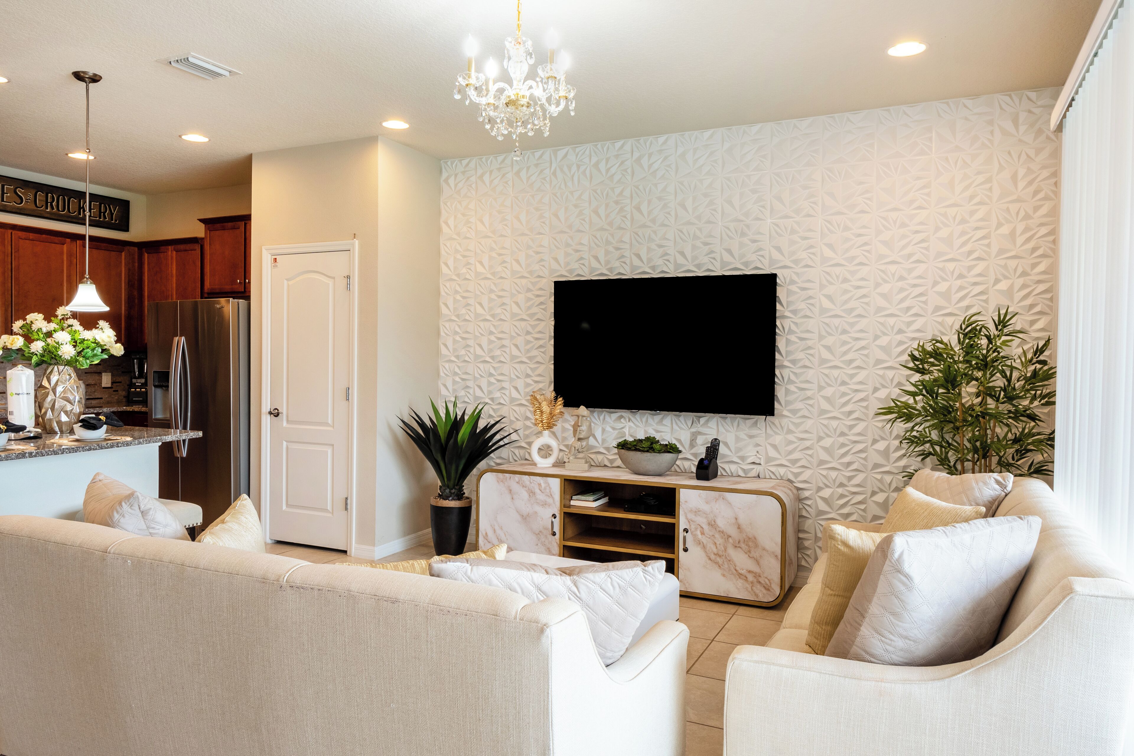 A modern living room with a large flat-screen TV, a marble console table, and a sofa.
