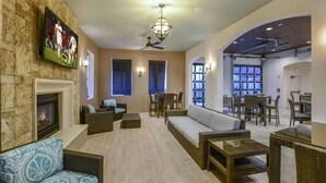 Un amplio espacio de estar con chimenea, asientos cómodos y televisor montado en la pared.