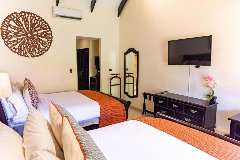 Una habitación de hotel con dos camas, televisión, cómoda y espejo.