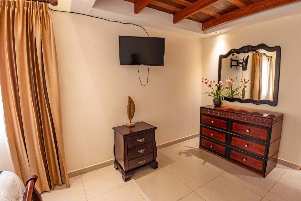 Una habitación con un televisor montado en la pared, un aparador con varios cajones y una mesita con un objeto decorativo.