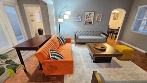 Una sala de estar moderna con sofá, mesa de centro y comedor con mesa y sillas.