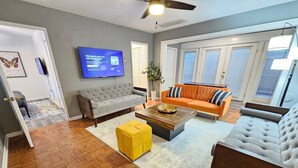 Una sala moderna con un sofá gris, un taburete amarillo y una mesa de centro de madera.