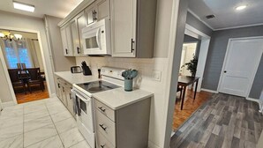 Una cocina moderna con armarios blancos, microondas integrado y campana extractora de acero inoxidable.