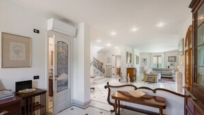 A spacious foyer with a grand staircase, a wooden bench, and a dining area with a table and chairs. - Villa Le Fontanelle In Forte Dei Marmi (Forte dei Marmi)