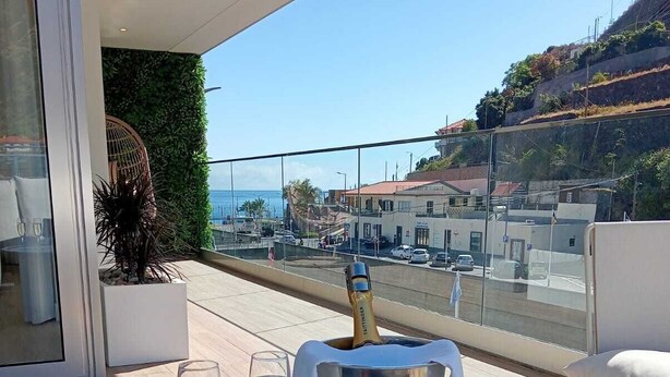 A balcony with a table, two glasses, and a champagne bucket.