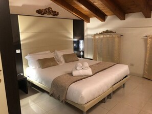 A bedroom with a large bed, a bedside table, a lamp, and a curtain. - Villa Giotto Apartments in the Center of Mestre (Venezia)
