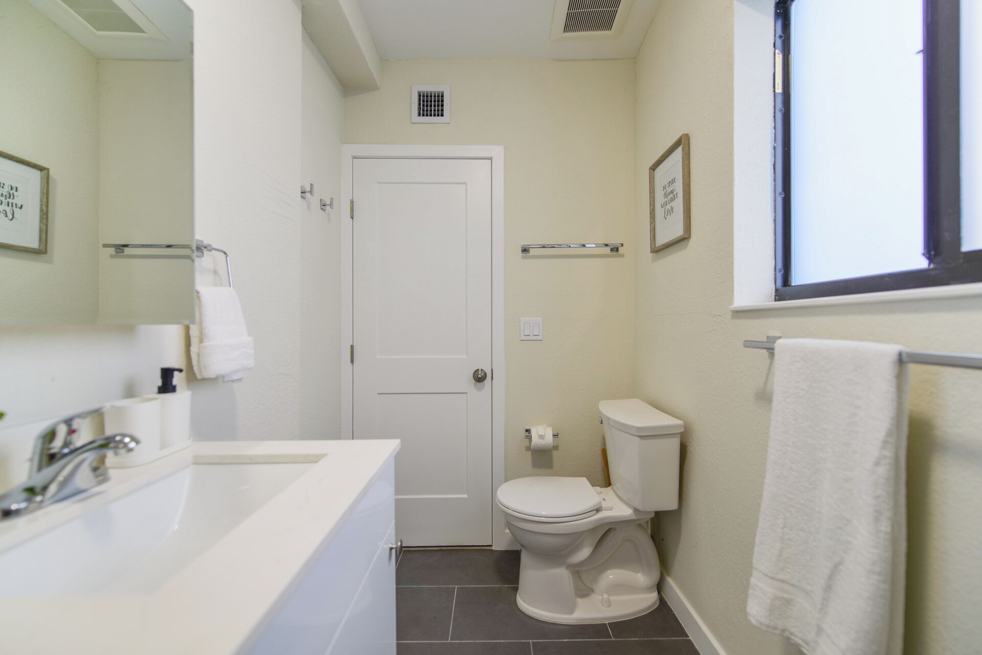 A bathroom with a white sink, toilet, and a window.