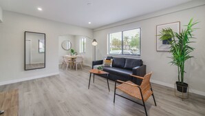 Un salon moderne avec un canapé, une table à manger et une grande fenêtre.