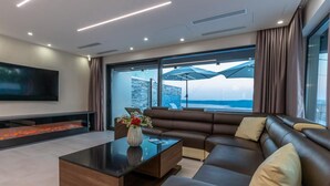 A modern living room with a large sectional sofa, a coffee table, and a flat-screen TV. - Lorena Stylish Sea View Villa (Crikvenica)
