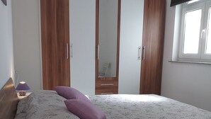 A bedroom with a bed, a nightstand, a lamp, and a wardrobe. - Apartments Lavanda & More (Rab)