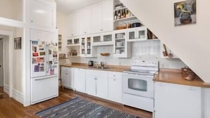A modern kitchen with white cabinetry, a wooden countertop, and a built-in oven. - The Miners Union: Hip & Historic (Telluride)