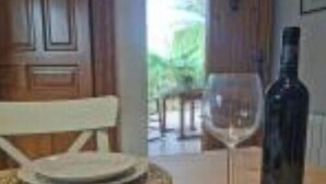Un comedor con una mesa preparada para dos personas, una botella de vino y una copa.