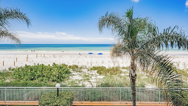 A beach with white sand, palm trees, and a clear blue sky. - Gulf Front Getaway at Plumlee Vacation Rental Chateaux 107 (Indian Shores)