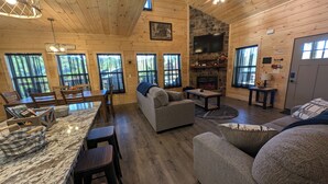 A cozy cabin interior with a stone fireplace, wooden walls, and a dining area with a marble countertop. - 3 Master Suites, Easy Access w/View, Game&Theater Rms, Fire Pit, & Pool Access (Sevierville)