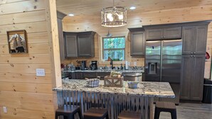 A modern kitchen with wooden paneling, granite countertops, stainless steel appliances, and bar stools. - 3 Master Suites, Easy Access w/View, Game&Theater Rms, Fire Pit, & Pool Access (Sevierville)