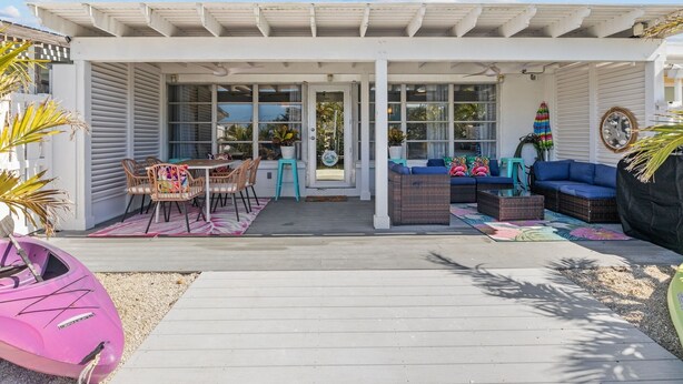 Un patio couvert aménagé avec du mobilier d’extérieur, comprenant une table et des chaises, un canapé et une causeuse.