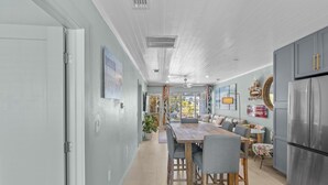 Une cuisine moderne dotée d’un îlot central, d’appareils électroménagers en acier inoxydable et d’un coin repas avec une table et des chaises en bois.