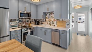 Une cuisine moderne avec des meubles de couleur bleu clair, des appareils en acier inoxydable et une table à manger en bois.