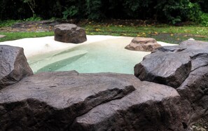 A rock-lined hot tub surrounded by large boulders. - Luxury Retreat with Private Jacuzzi & High-Speed WiFi in La Fortuna! (La Fortuna)