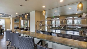 Une cuisine moderne dotée d’un long comptoir, de sièges de bar et de luminaires suspendus.