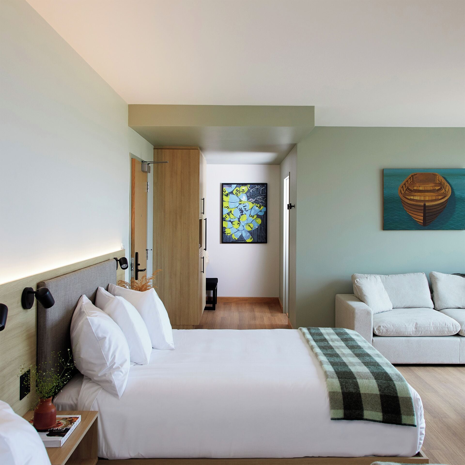 Ein modernes Hotelzimmer mit einem großen Bett, einer Couch und einem Bild eines Bootes.