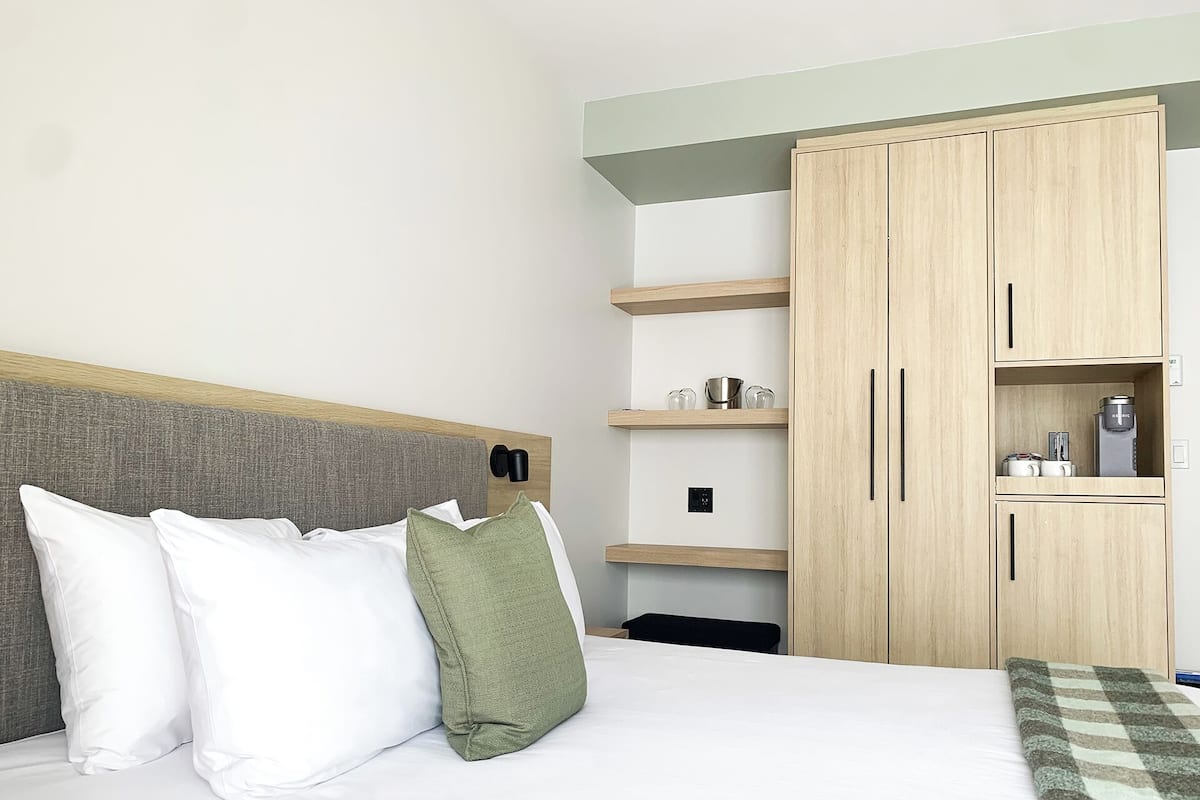Ein Hotelzimmer mit einem Bett, einem Kleiderschrank und einem Regal mit Gegenständen.