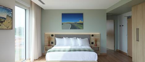A modern bedroom with a large bed, a painting of a landscape, and a view through the window.